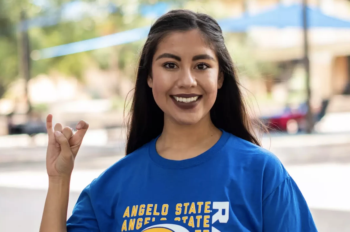 A young woman wearing a blue tshirt holding her hand up like a ram